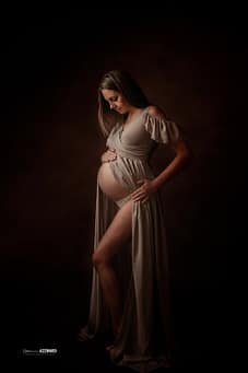Femme enceinte en robe fluide posant dans une ambiance douce et artistique, photographie de maternité réalisée par Stéphanie Azemard à Montpellier.
