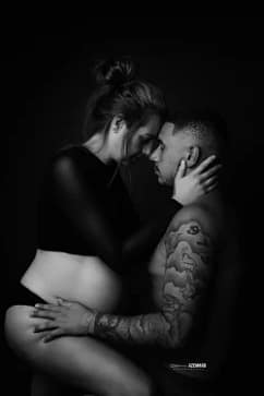 Portrait noir et blanc d’un couple en séance photo de grossesse, regard tendre et contact frontal, réalisé par Stéphanie Azemard à Montpellier.