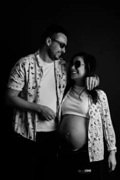 Photo de grossesse en couple en noir et blanc dans un style décontracté et amusant, réalisée en studio par Stéphanie Azemard à Montpellier.
