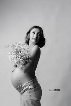 Portrait artistique en noir et blanc d'une femme enceinte tenant un bouquet de gypsophiles en studio, par Stéphanie Azemard à Montpellier.