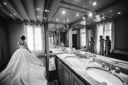 Photo en noir et blanc des préparatifs du mariage, mettant en valeur le reflet de la mariée dans le miroir. Prise par Azémard Stéphanie, photographe experte en mariage.