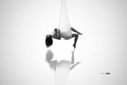Mère suspendue dans un tissu blanc tenant son bébé contre elle, photo artistique en noir et blanc par Stéphanie Azémard.