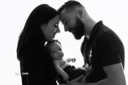 Portrait en noir et blanc d'une famille, capturant un moment intime entre les parents et leur bébé.