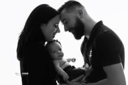 Portrait en noir et blanc d'une famille, capturant un moment intime entre les parents et leur bébé.