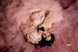Portrait d'une mère et de son bébé en tenue assortie rose, allongées dans un décor de tulle rose.