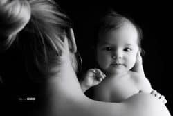 Un bébé dans les bras de sa maman, capturé en noir et blanc, exprimant la tendresse et le lien unique qui les unit.