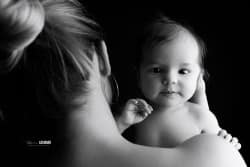 Un bébé dans les bras de sa maman, capturé en noir et blanc, exprimant la tendresse et le lien unique qui les unit.