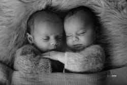 Portrait en noir et blanc de deux jumeaux nouveau-nés endormis, emmitouflés dans des lainages, photographiés en studio à Montpellier par Stéphanie Azemard.