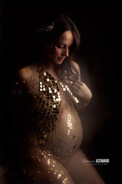 Femme enceinte parée d’ornements dorés et d’un bijou de corps, posant dans une ambiance douce et artistique. Photographie de maternité réalisée par Stéphanie Azemard à Montpellier.