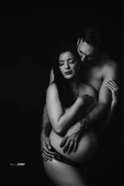Portrait artistique en noir et blanc d’un couple enlacé, mettant en valeur le ventre arrondi de la future maman dans un style élégant et intime en studio.